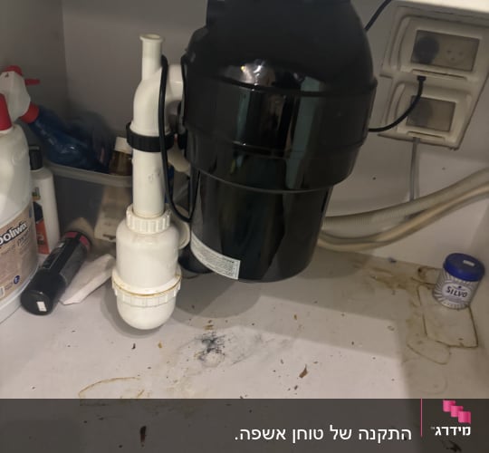 כיור עם צנרת וכלים מתחת לארון מטבח